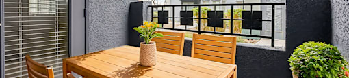 A wooden table with chairs and a vase of flowers on a balcony.