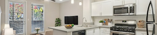 A kitchen with white cabinets and a blue rug on the floor.
