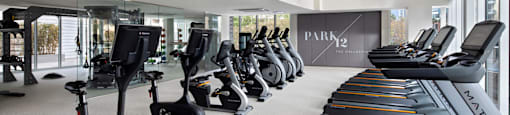 A gym with a row of treadmilers and elliptical machines.
