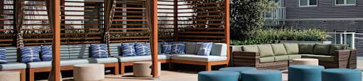 A pool area with a wooden structure and cushions.
