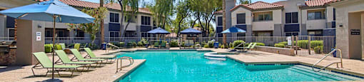 A large swimming pool surrounded by sun loungers and umbrellas.