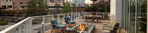 A balcony with chairs and a table overlooks a cityscape.