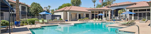 A large swimming pool surrounded by a concrete patio and a few trees.