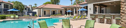 A poolside area with a fire pit and chairs.