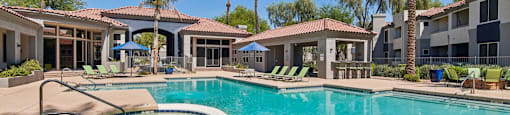 A swimming pool surrounded by palm trees and lounge chairs.