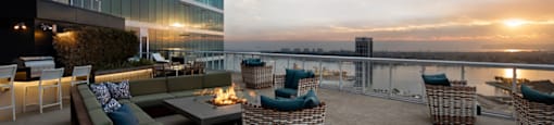A rooftop patio with a couch, chairs, and a table with a lit candle.