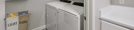 a laundry room with a washer and dryer and white cabinets
