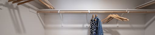 a walk in closet with a rack of clothes and a basket on the floor
