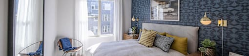 a bedroom with blue wallpaper and a white bed