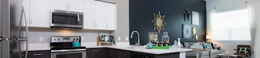 a kitchen with white cabinets and stainless steel appliances and a table with a chair in the background