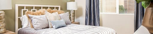 A bedroom with a bed, a mirror, and two lamps.
