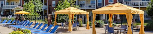an outdoor patio with yellow umbrellas and chairs at an apartment complex