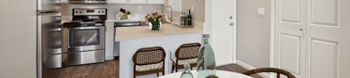 an open kitchen and dining room with stainless steel appliances and a white table