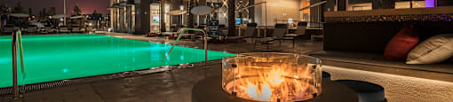 a fire pit in front of a pool at night