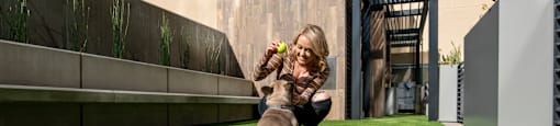 a woman is playing with her dog on the grass