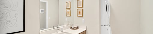 a bathroom with a sink and a mirror and washer/dryer