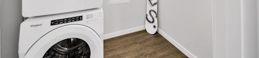 a white laundry room with a washer and dryer and a surfboard in