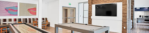 a game room with a shuffleboard table and a television