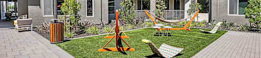 an apartment yard with hammocks and chairs in front of an apartment building