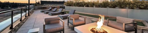 a rooftop lounge with a fire pit and tables