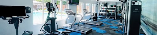 a gym with cardio equipment and a flat screen tv