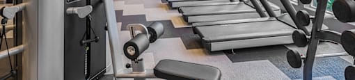 A gym with treadmills, weights, and a ceiling fan.