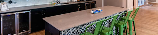 A kitchen with a long table and green chairs.