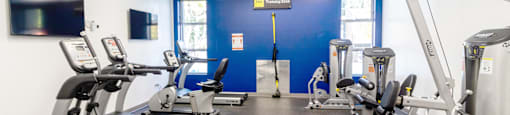 a gym with various exercise equipment and a tv