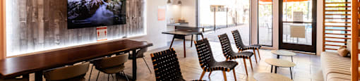 a lounge room with tables and chairs and a tv on the wall