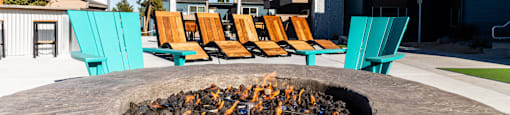 a fire pit with chairs and umbrellas on a patio
