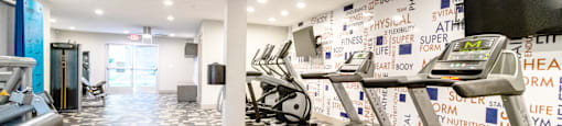 a workout room with treadmills and a wall covered in graffiti