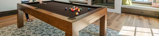 a woman playing a pool table in a living room with a tv