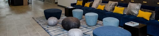 a living room with blue couches and chairs and a checkered rug