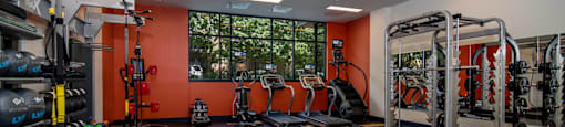 a gym with weights and cardio equipment and a window