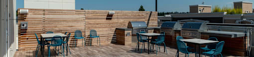a roof deck with tables and chairs and a barbecue grill