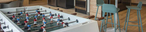 a game room with a foosball table and a kitchen