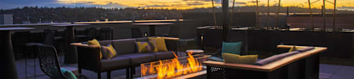 a rooftop patio with a fire pit and tables and chairs