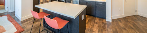 A kitchen with a white island and black cabinets.