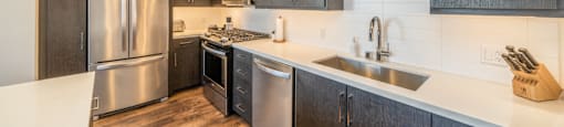 A modern kitchen with dark wood cabinets and stainless steel appliances.