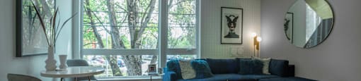 a living room with a blue couch and a table and a large window