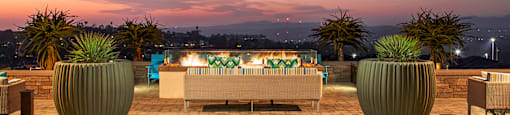 A patio with a couch, chairs, and a table with lights is set up on a rooftop.