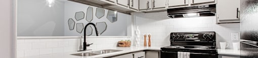 A modern kitchen with black appliances and white cabinets.at Laurel, Union City, GA  