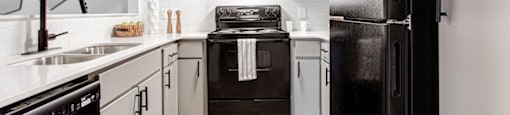 A black refrigerator stands in a kitchen with white cabinets and a black stove.at Laurel, Union City  