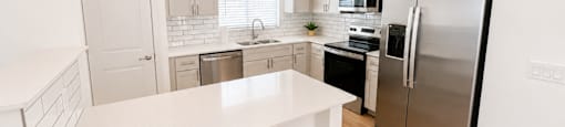 A kitchen with a white counter top and stainless steel appliances.