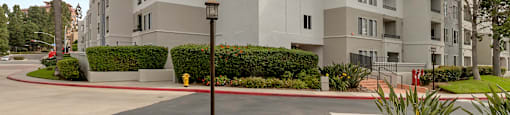 a large white apartment building with palm trees in front of it at Nobel Court, San Diego, CA
