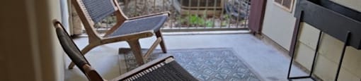 A wooden chair with a black cushion is on a patio.