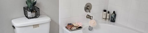 A white toilet sits next to a white bathtub in a bathroom.