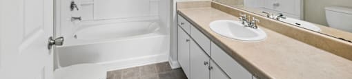 A white bathroom with a tub, sink, and mirror.