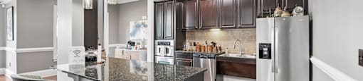 A kitchen with a granite countertop and bar stools.