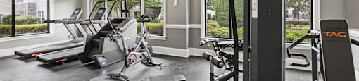 A gym with a treadmill, a stationary bike, a bench, and a weight machine.